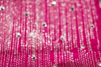 Textile of pink color decorated with strasses, bokeh effect.