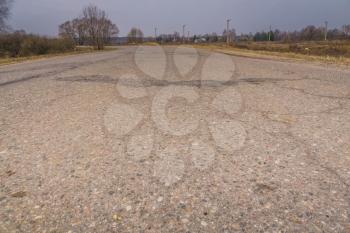 Old cracked, damaged asphalt road in countryside.