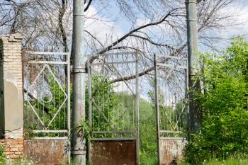 Abandoned rural stadium metal gate and green foliage.