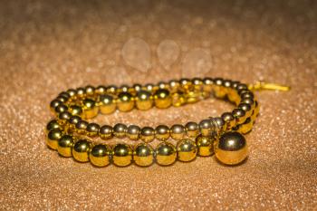 Fashion bracelet made of gold round beads background.