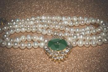 Natural white freshwater pearl necklace close up filtered background.