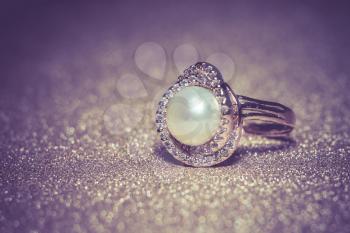 Luxury rose gold plated ring with freshwater pearl of white color, filtered background.