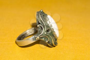 Vintage ring with white stone on yellow background.