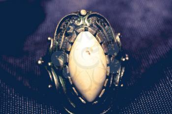 Vintage ring with decorative white stone on black textile macro.