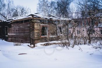 Abandoned ruined house and snow, cold winter day.