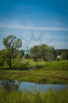 Summer green grass field and old white church, rural landscape.