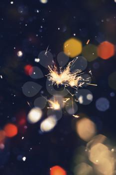 Bengal fire, sparkler and colorful bokeh with blurred snow, christmas, new year background.