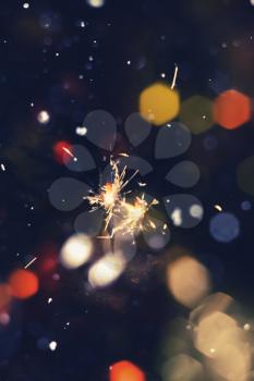Bengal fire, sparkler and colorful bokeh with blurred snow, christmas, new year background.