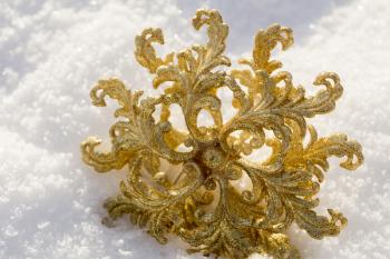 Ornamental golden snowflake glittering on fresh white snow.