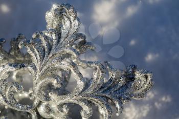 Ornamental silver snowflake glittering on fresh white snow.