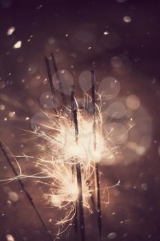 Bengal fire, sparkler and defocused falling snow, holiday background.