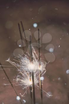 Bengal fire, sparkler and defocused falling snow, holiday background.