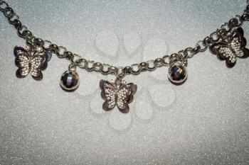 Fashion bracelet with silver charms on glitter background.