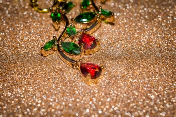 Decorative rose gold earrings with ruby red and green zircons, floral themed jewellery.