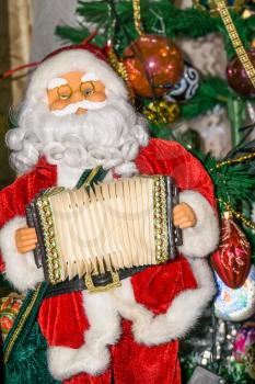 Christmas santa toy playing the accordion, holiday background.