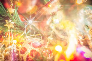 Close up of Christmas or New Year fir tree with decorative lights and toys, filtered background.