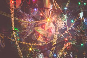 Close up of Christmas or New Year fir tree with decorative lights and toys, filtered background.