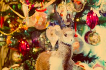 Cute fur ram toy on background with Christmas decorations, vintage photo effect.
