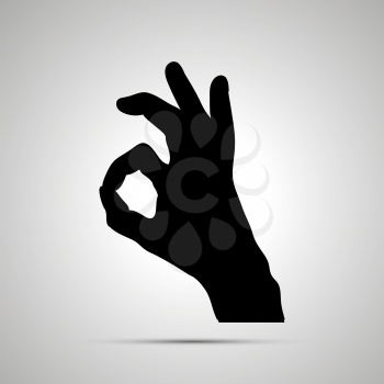 Black silhouette of hand in OK gesture isolated on white