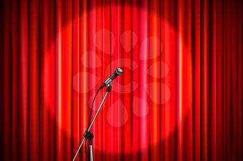 Bright red curtain with shiny microphone in round spotlight lighting, retro theater stage wide background