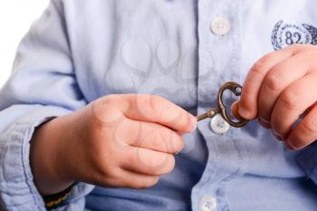 Baby with a blue shirt holding a  metal key in his hand  on a white background