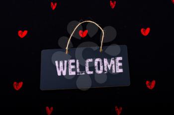 Welcome wording on black notice board  with red hearts around