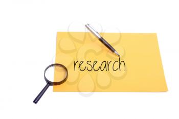 Pen and magnifying glass  on paper research wording
