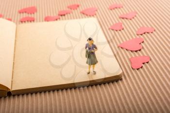 Woman figurine on notebook with  red paper hearts around