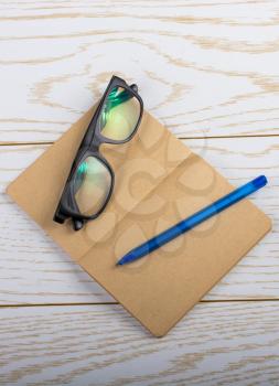 Brown color blank notebook, pen, pocket watch and sunglasses