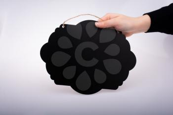 Black speech bubble shaped notice board in hand on white background