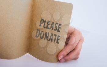 Hand holding a sheet of paper   with please donate wording