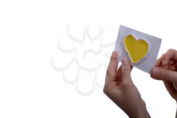 Hand holding a yellow heart shape paper cut out of paper on a white background