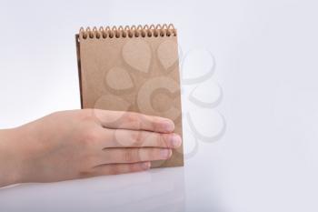 Hand holding brown color notebook  on a white background