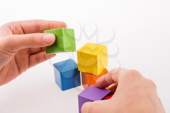 Hand playing with colorful cubes on a white background