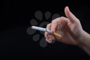 Hand is breaking a cigarette on a black background