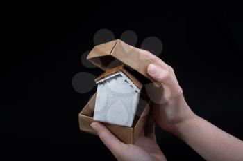 Little model house in hand in a paper box