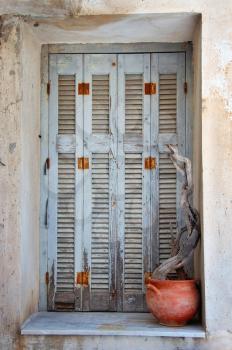Weathered window shutter and decorative pottery. Traditional Greek island house detail.