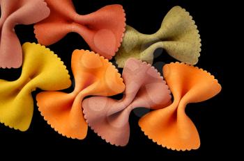 Multi colored farfalle bow ties pasta against a black backgrround.