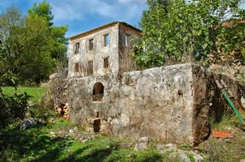 Vintage stone tank for grape stomping and derelict house ruins. Zakynthos, Greece.