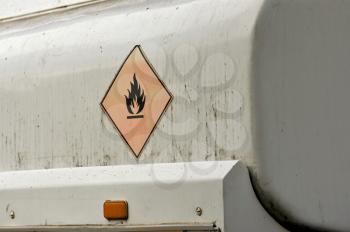 Flammable material weathered warning sign on gas tank.