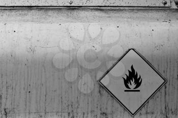 Flammable material weathered warning sign on rusty metal surface. Black and white.