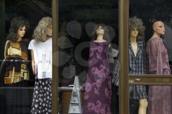 Plastic mannequin dolls behind the dusty window of an abandoned store.