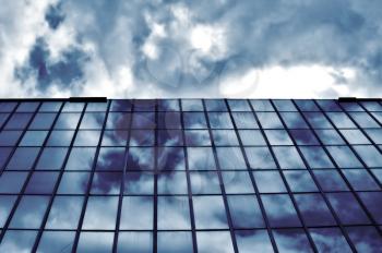 Overcast sky mirrored on modern glass building. Architectural detail.