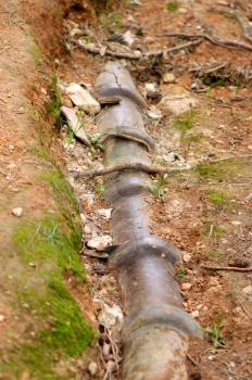 Eroded soil reveals water pipes underneath.