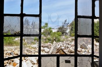 View to a pile of rubble from the broken windows of a partially demolished factory.