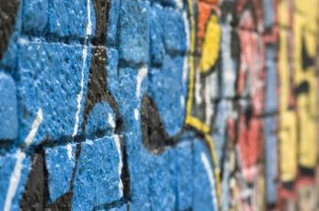 Rough stone wall surface covered with colorful graffiti. Urban street art.
