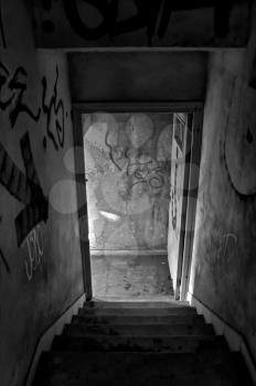 Stairs and exit door of abandoned house. Black and white.