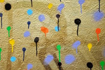 Golden painted wall covered with dots of dripping spray paint.