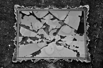 Antique picture frame with broken glass on dirty rag background. Black and white.