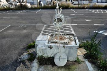 Vintage well in empty parking lot. Changing urban landscape and traces of the past.
